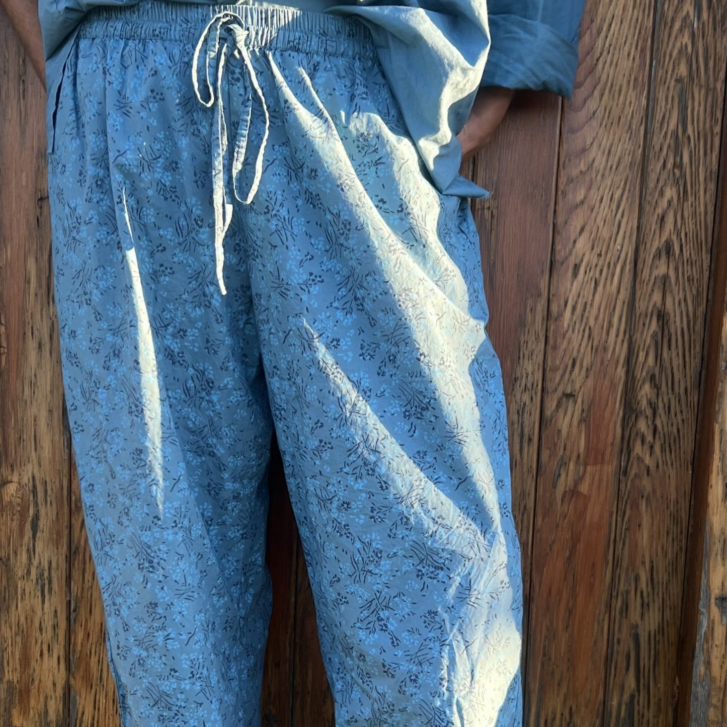 Blue patterned pants worn by a person against a wooden wall.