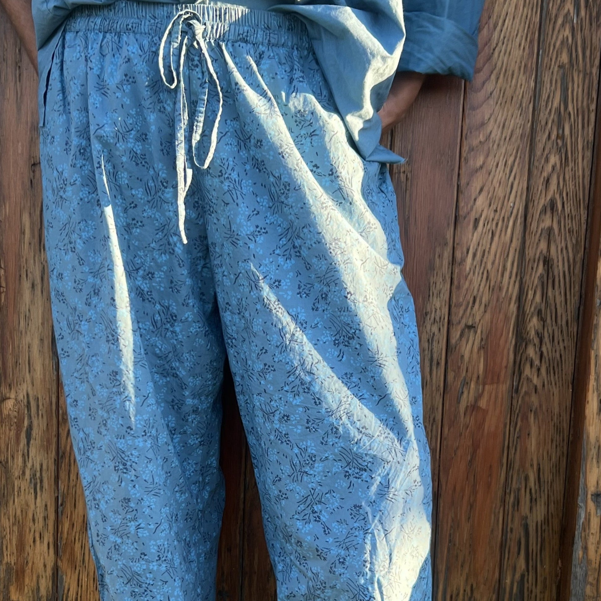 Blue patterned pants worn by a person against a wooden wall.