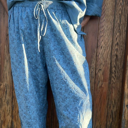 Blue patterned pants worn by a person against a wooden wall.