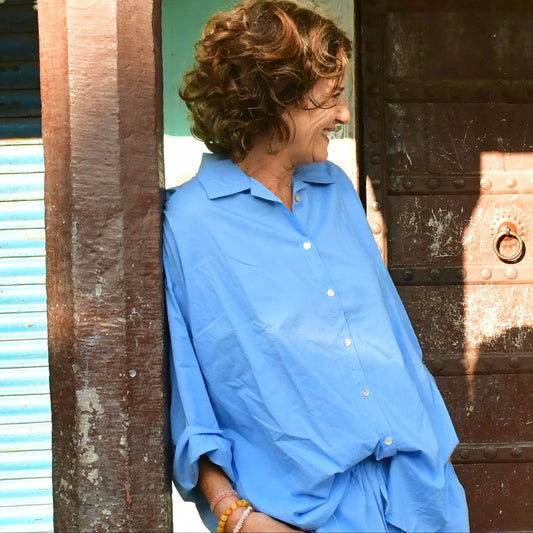 Person wearing a blue shirt standing in front of a wooden door